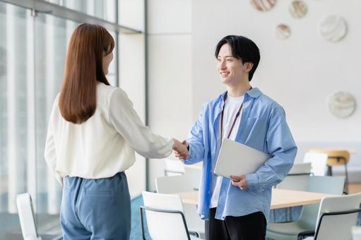 握手する若いビジネスパーソン 握手する若いビジネスパーソンの写真