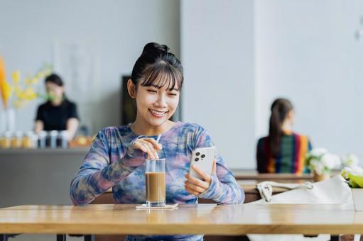カフェでスマホを見る若い女性 カフェでスマホを見る若い女性 女性,カフェ,スマホの写真素材