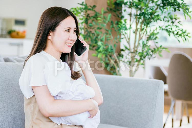 赤ちゃんを抱きながら通話する女性 赤ちゃん,ママ,子育ての写真素材
