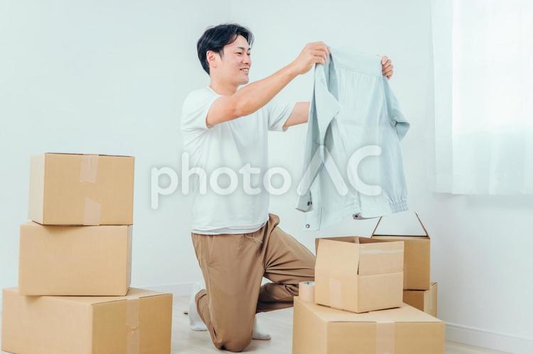 段ボールから洋服を出す男性 ダンボール,引越し,荷物の写真素材
