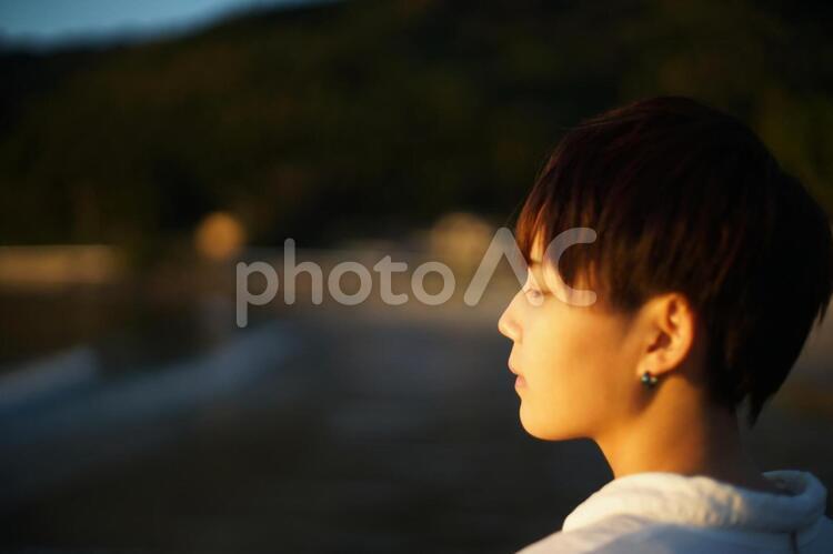 夕日と海とボーイッシュな女の子の横顔 笑顔,お出かけ,lgtbの写真素材