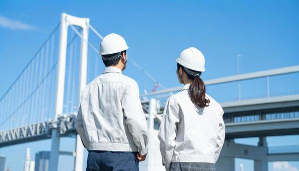 建設作業員男女2人が空を見上げる後ろ姿 建設作業員男女2人が空を見上げる後ろ姿の写真