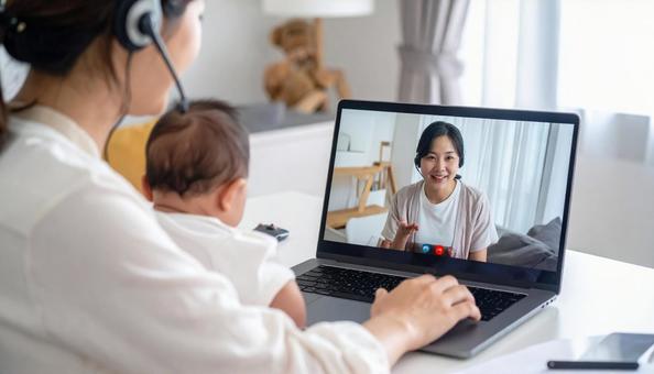  赤ん坊を抱きながらビデオ通話で話す女性の写真