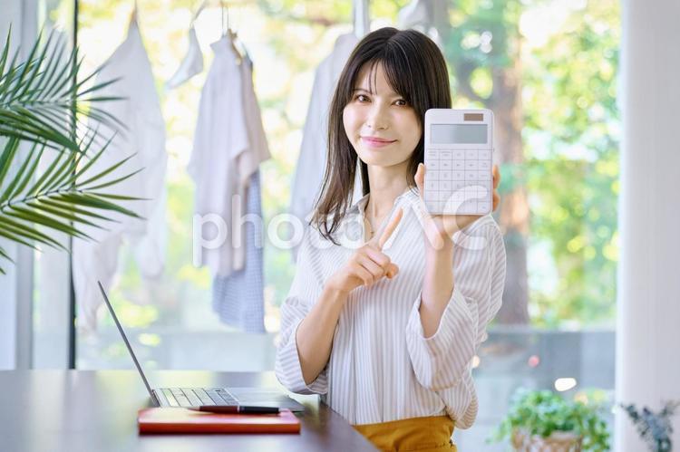 電卓を持つ女性　主婦　家計簿 ビジネスウーマン,主婦,テレワークの写真素材