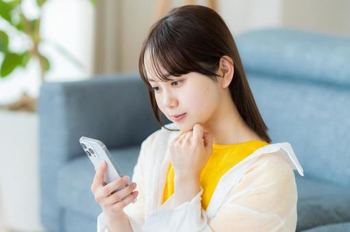 スマホを見て考える若い女性 スマホを見て考える若い女性 スマホ,考える,悩むの写真素材