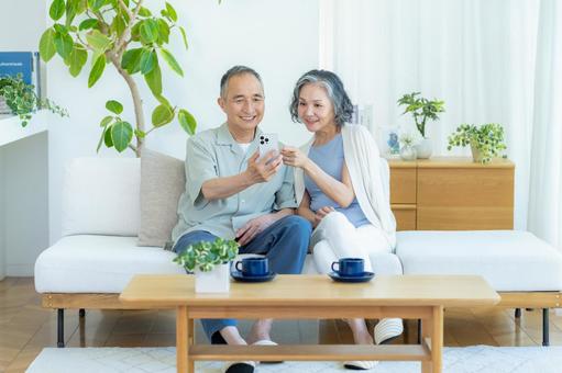 リビングでスマホを見るシニア夫婦 リビングでスマホを見るシニア夫婦 スマホ,シニア,笑顔の写真素材