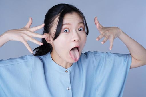 青い服の女性が両手で顔の横を指差すの写真