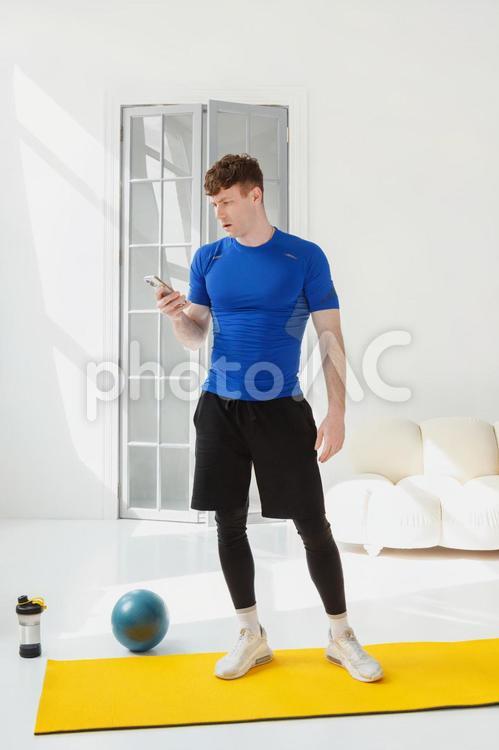 運動の途中で携帯を見る男性 男性,人物,携帯の写真素材