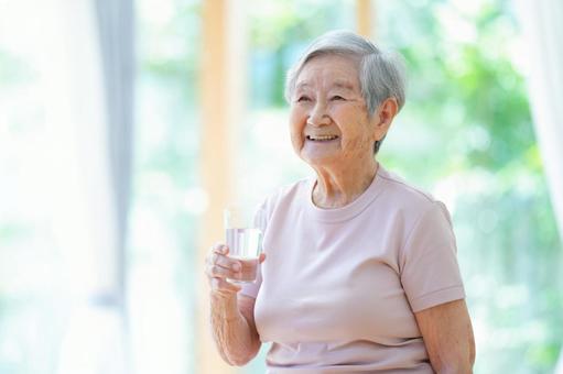 水を持ち笑うおばあちゃん 女性,コップ,水の写真素材