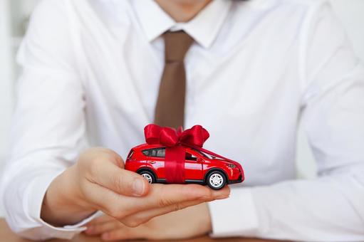 赤い車の模型を見せる男性 保険業,事務職,接客業の写真素材