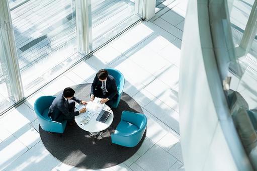 オフィスロビーで商談するビジネスマンの写真