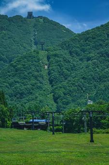 新緑の山肌を登るゴンドラと青い空 新緑の山肌を登るゴンドラと青い空の写真