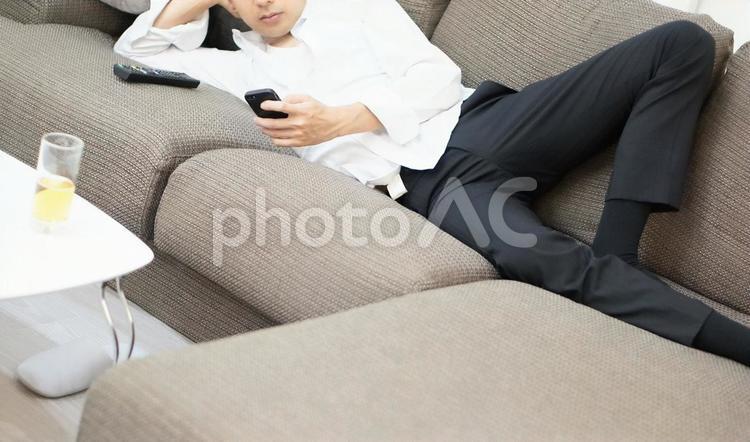 だらしなくスマホを触る男性 だらしない,グダグダ,やる気なしの写真素材