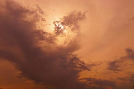 赤く染まりかけた雲の多い空の写真