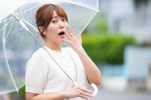カメラ目線で驚く傘を差した女性の写真