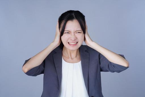 両耳をふさぐスーツを着た女性 女性,耳を塞ぐ,頭を抱えるの写真素材