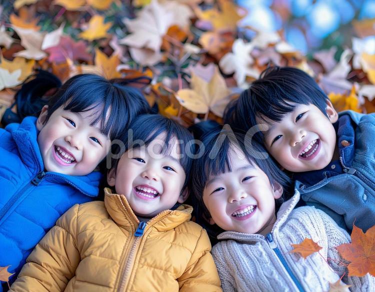 落ち葉の上に寝そべる子供たち 秋,子ども,落ち葉の写真素材