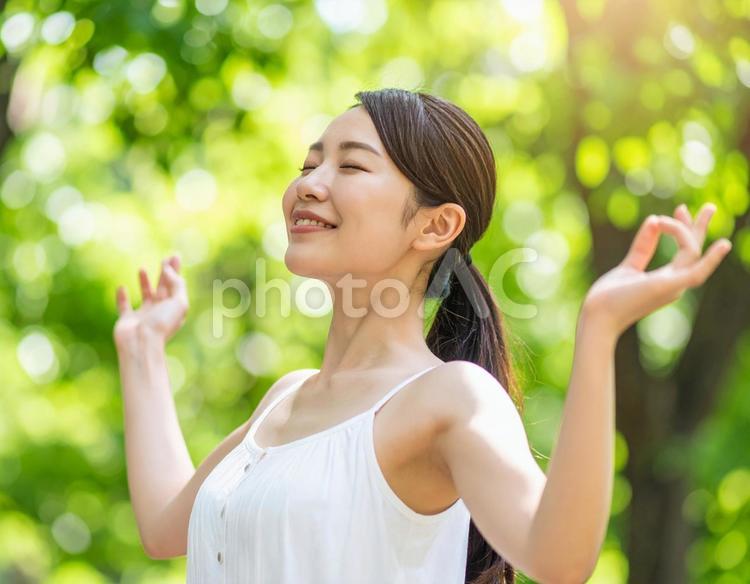 緑の中で伸びをする女性 背伸び,ストレッチ,伸びの写真素材