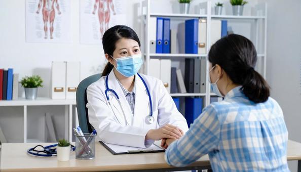 白衣の医者が患者を診断している様子 白衣の医者が患者を診断している様子の写真