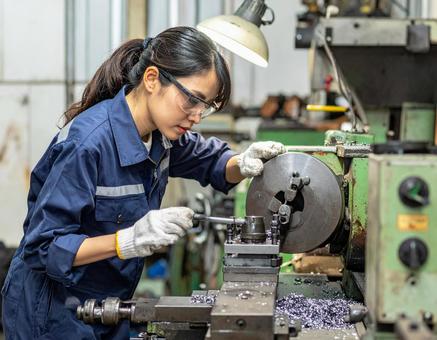 工場で加工機械で金属加工する女性スタッフの写真