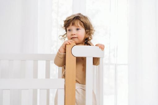 ベッドの柵を掴み立つ嬉しそうな子供 ベッドの柵を掴み立つ嬉しそうな子供 赤ちゃん,かわいい,ベビーベッドの写真素材
