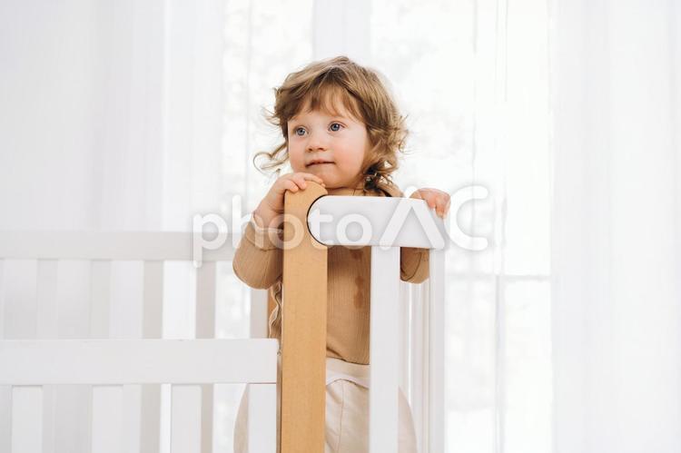 ベッドの柵を掴み立つ嬉しそうな子供 赤ちゃん,かわいい,ベビーベッドの写真素材