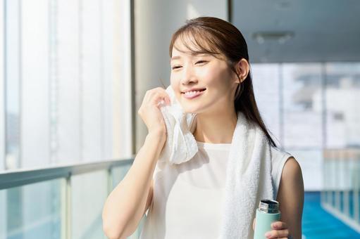 ジムで汗を拭く笑顔の女性　水分補給 ジム,トレーニング,女性の写真素材