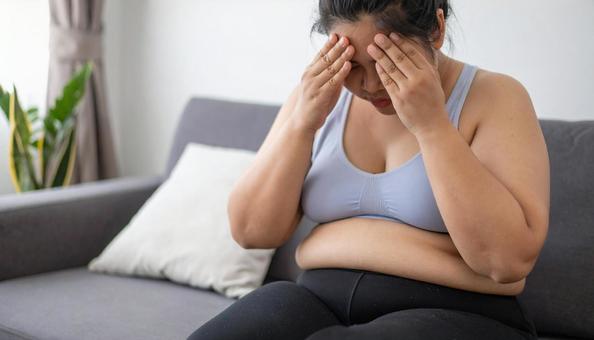 肥満で疲れやすく、額に手をやる女性 肥満で疲れやすく、額に手をやる女性の写真
