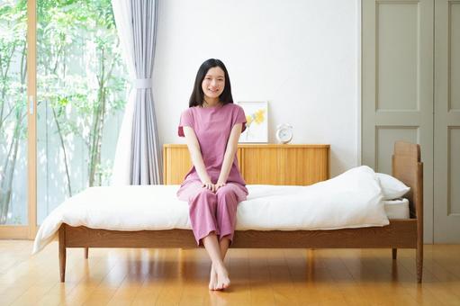 足をクロスしベッドに座るカメラ目線の女性 女性,ベッド,座るの写真素材