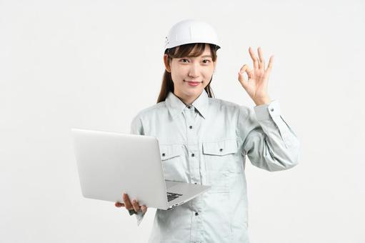 作業服の女性がPCを持ちOKサインをする 作業服の女性がPCを持ちOKサインをする 作業員,女性作業員,建設建設現場の写真素材