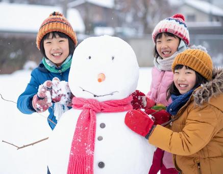 雪だるまを作って喜ぶ子供の冬の屋外風景 雪だるまを作って喜ぶ子供の冬の屋外風景の写真