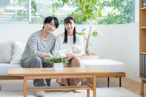 リビングで赤ちゃんを抱く若い家族 リビングで赤ちゃんを抱く若い家族 家族,親子,赤ちゃんの写真素材