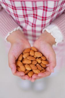 ナッツを大切に包み込む子どもの手 アーモンド,持つ,ナッツの写真素材