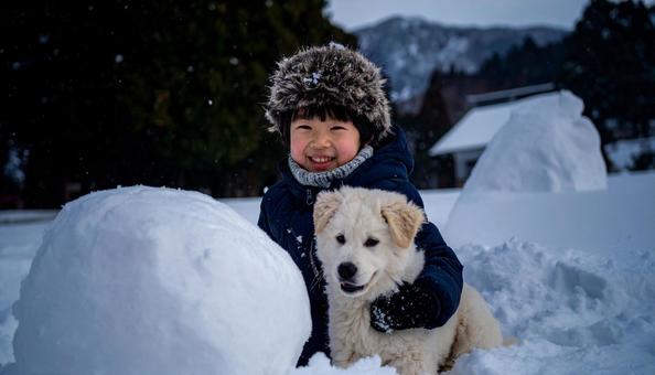 雪と犬と子供、雪だるまを作る 雪と犬と子供、雪だるまを作るの写真
