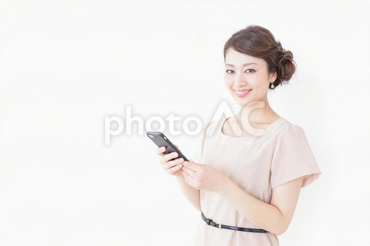 スマホを使うおしゃれ着の女性 記念パーティー,出会い,婚活パーティーの写真素材