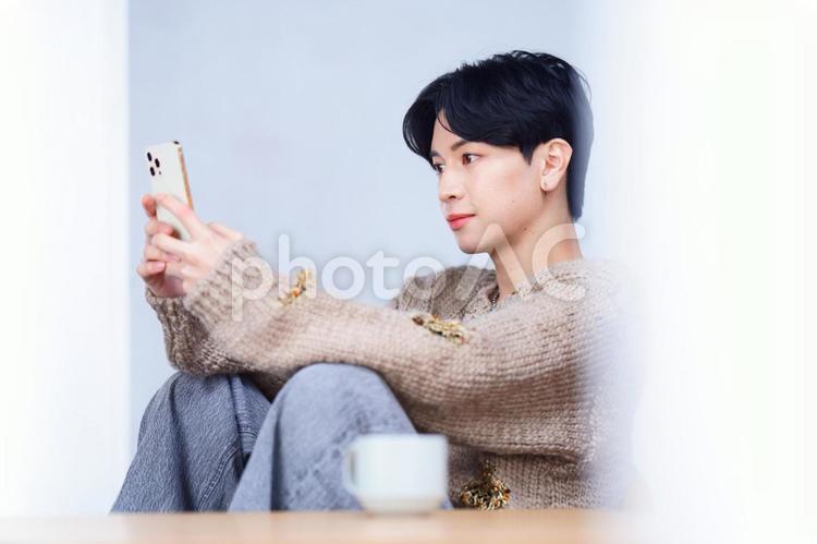 両手でスマホを持ち見ている男性の横顔 男性,スマートフォン,持つの写真素材