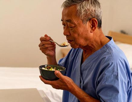 端座位で食事をするシニア男性の患者 端座位で食事をするシニア男性の患者の写真