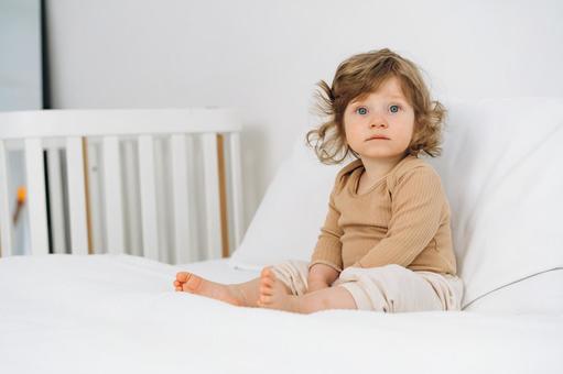 枕に寄り掛かりお座りするくせ毛の子 赤ちゃん,かわいい,お座りの写真素材