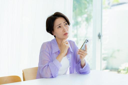 スマホを持って考える女性 スマホを持って考える女性 スマホ,考える,悩むの写真素材