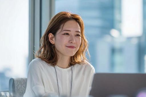 デスクでほほ笑むビジネス女性 デスクでほほ笑むビジネス女性の写真