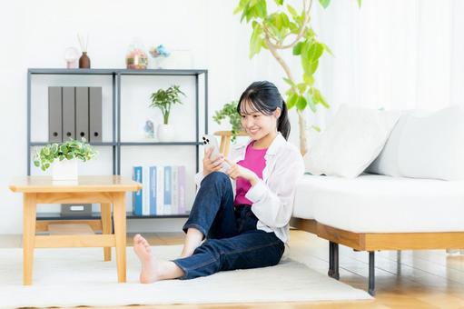 部屋でスマホを操作する若い女性 部屋でスマホを操作する若い女性の写真