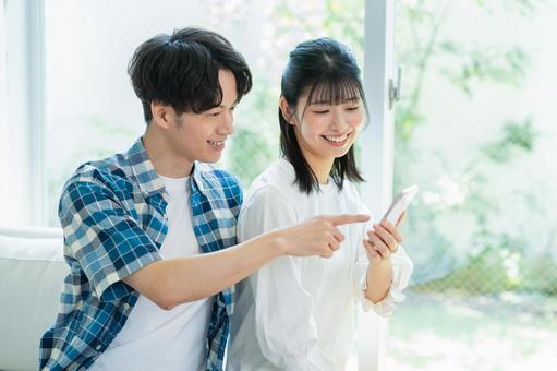 リビングでスマホを見るカップル リビングでスマホを見るカップル スマホ,笑顔,カップルの写真素材