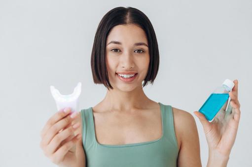 青色のマウスウォッシュを笑顔で持っている女性 青色のマウスウォッシュを笑顔で持っている女性の写真