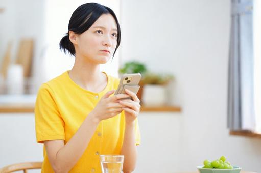 スマホを持ち悩んでいる女性 女性,スマートフォン,持つの写真素材