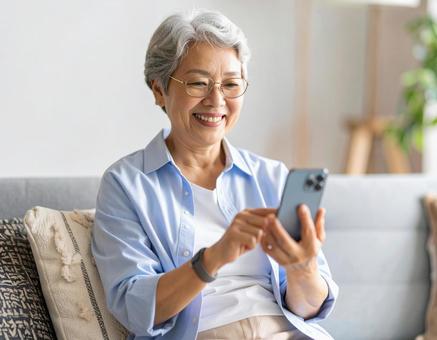 自宅のリビングでスマホを操作する女性 自宅のリビングでスマホを操作する女性の写真