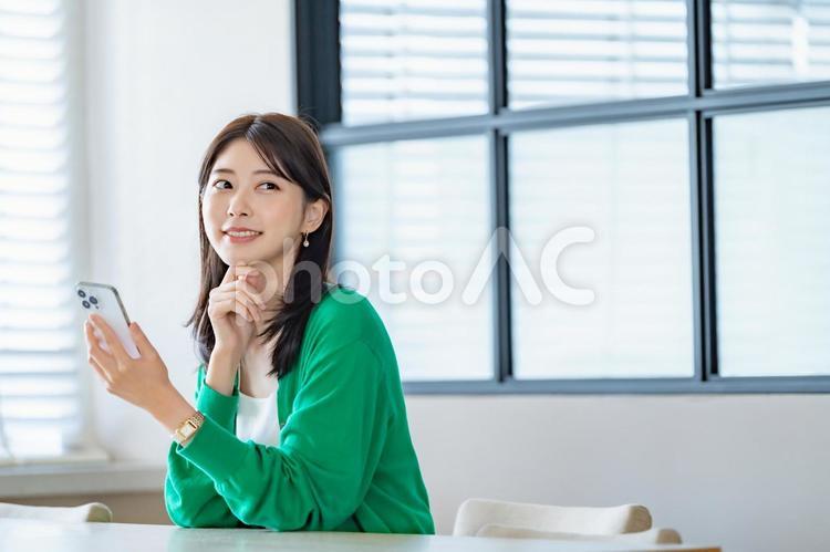室内でスマートフォンを持ち微笑む女性 女性,スマートフォン,携帯電話の写真素材