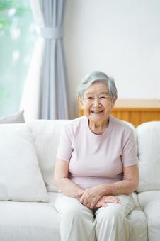 ソファに座り笑っている半袖の高齢女性 女性,笑顔,ソファの写真素材