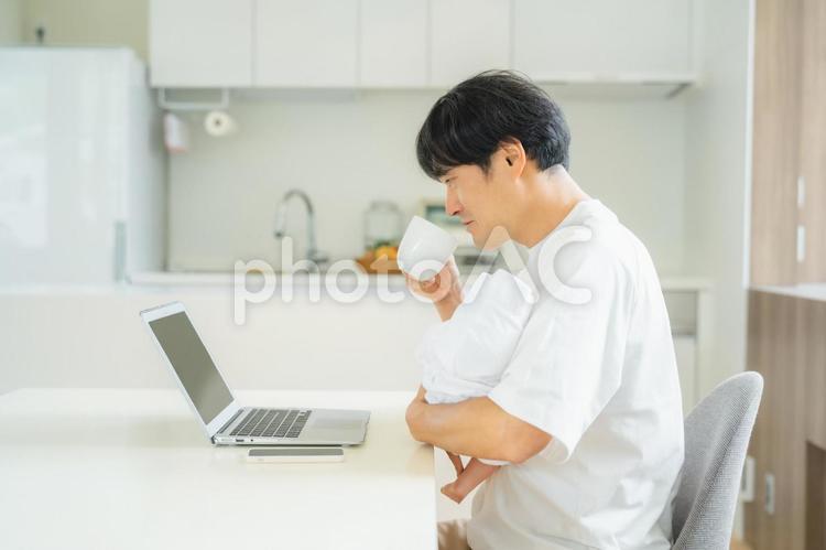 赤ちゃんを抱きながら仕事する男性 テレワーク,育児,リモートワークの写真素材