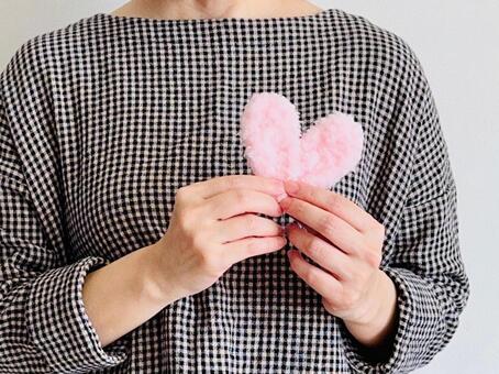 ピンクのハートを持つ女（チェック柄の服） ハート,女性,優しさの写真素材