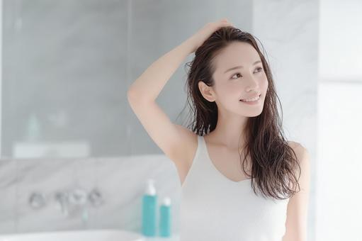 シャンプー後に髪をケアする笑顔の若い女性 シャンプー後に髪をケアする笑顔の若い女性の写真
